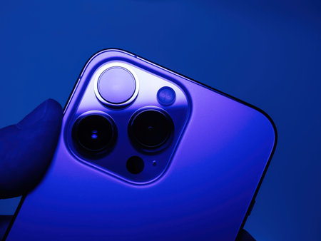POV male hand holding latest Apple Computers iPhone 13 pro smartphone showing the triple camera on...