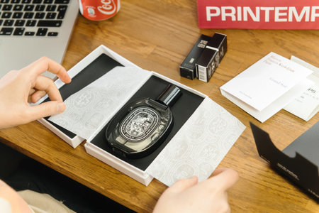 Woman unboxing unpacking new Perfume box luxury French Diptique brand on her working tableのeditorial素材