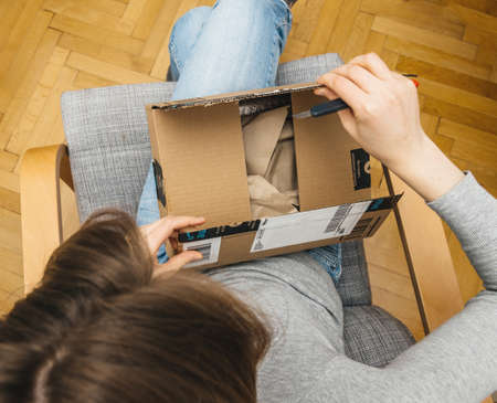 Overhead view of curious woman unboxing in the living room new Amazon Prime Parcelのeditorial素材