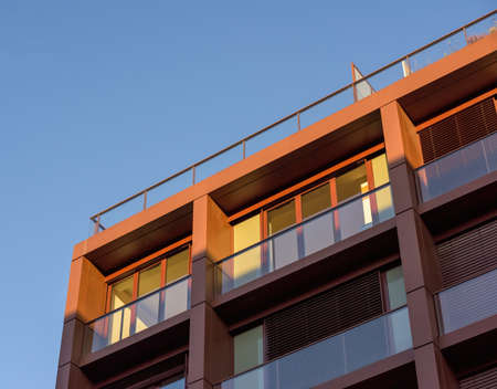 Low angle view of modern apartment building with clear blue sky in the backgroundの写真素材