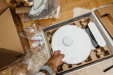 hand unpacking new robotic vacuum cleaner during the unboxing processの写真素材