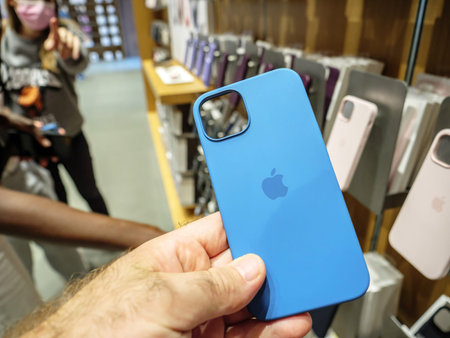 POV male hand holding silicone protection case of iPhone 13 Pro at the Apple Store as latest new 5G...