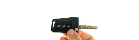 POV male hand holding new car key against green defocused backgr