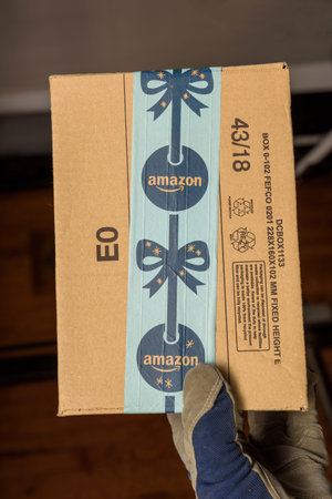 Male hand in protection glove holding in warehouse Amazon Cardboard box