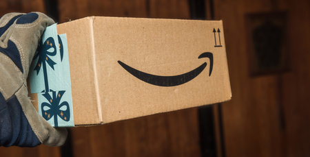 Workers hand in warehouse Amazon Cardboard box with Christmas insignia