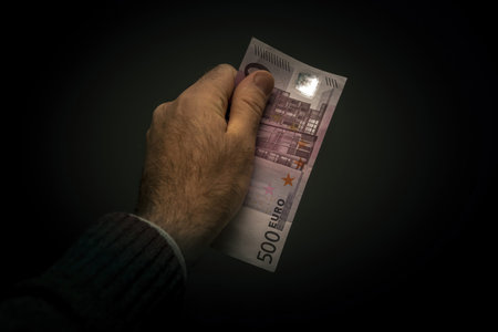 Male hand holding part of 500 euro bill
