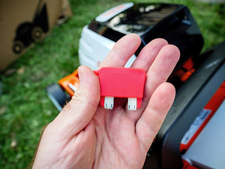 Male hand holding the security key of a new electric lawn mowe