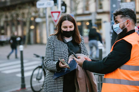 Man scanning the vaccine covid 19 certificate on smartphone of a woman wearing a respiratory maskのeditorial素材