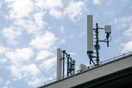 Multiple antenna on the rooftop of a house with scattered cloudsの写真素材