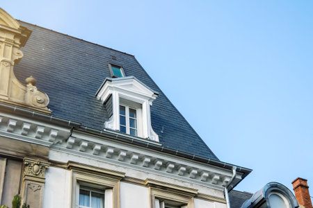 French rooftop with mansard window with blue sky in the background