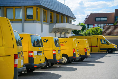 Row of multiple electric Volkswagen yellow vans with Deutsche post DHL logotype - parked near Postal Distribution Centerのeditorial素材
