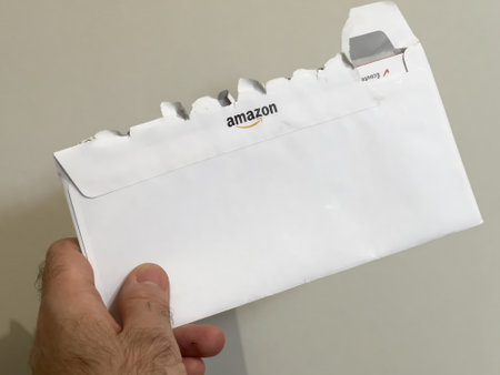 Rear view of Amazon open postal envelope in male hand - marketing communication from the company founded by Jeff Bezosのeditorial素材