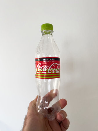 POV male hand holding empty bottle with Coca-Cola logotype and zero sugar text written in Romanian...