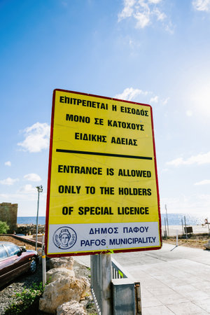Street view of yellow sign with text in Greek and English Entrance is Allowed only to the holders of special licenceのeditorial素材