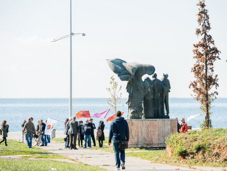 People with flags protesting in in front of National Resistance Monument located in 30th of October Park with Aegean sea in backgroundのeditorial素材