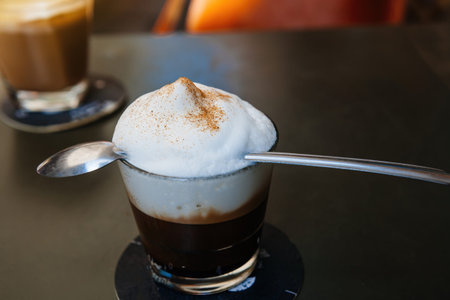 delicious cappuccino in glass with long spoon over the milky foam