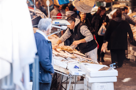 Busy atmoshpere at the central fish market in central Thessaloniki, fisherman seller arranging the fresh merchandise for greek customersのeditorial素材