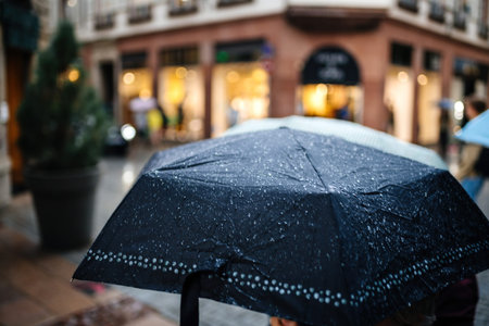 Close-up of large open umbrella with multiple water drops on the textile protection material