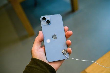 Customer male hand holding new Apple Computers iPhone 14 Plus in blue color in Apple Storeのeditorial素材