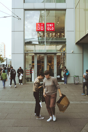 Customers exits Uniqlo store facade with pedestrians customers