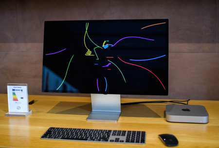Front view of new Apple Computers MacMini computer workstation with M2 M3 CPU connected to the Studio Display 5k Retina monitor showing Apple colorful logotypeのeditorial素材