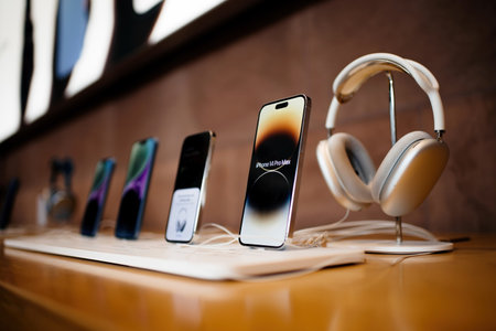 Row of all current line of Apple Computers iPhone smartphone - focus on 14 pro Max telephones with silver AirPods Max headphonesのeditorial素材