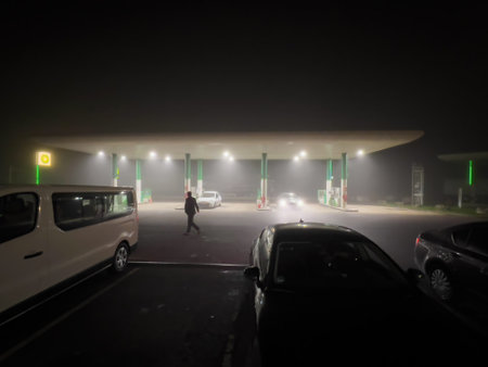 Male silhouette walking at night with gas station BP British Petroleum covered with fogのeditorial素材