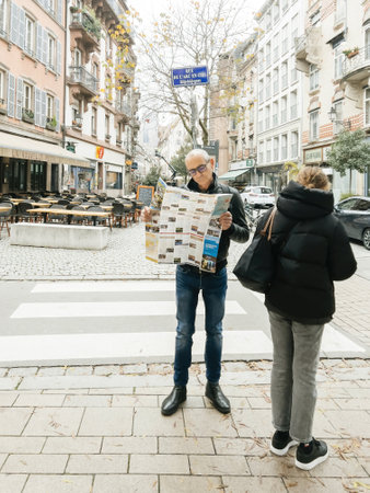 Curious male tourist reading a traveler tourist sightseeing map of Strasbourg in city centerのeditorial素材