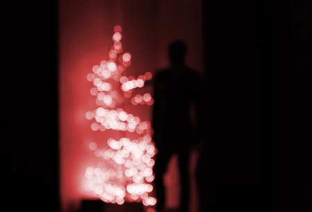 Male silhouette staying near a defocused yellow Christmas fir trの写真素材