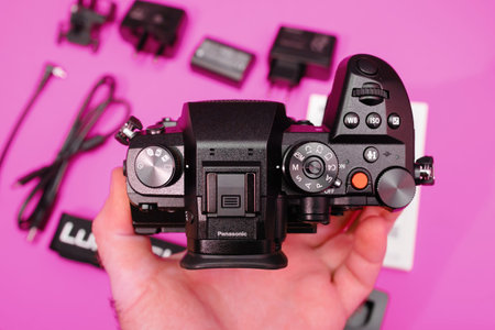 Directly above view of male hand holing at controls and knobs of new Panasonic Lumix DMC-GH6 Micro...