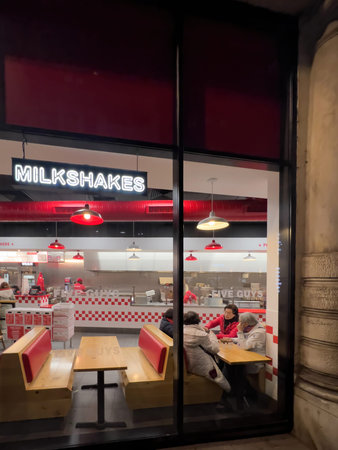 Asian ethnicity women talking at the wooden able inside Five Guys fast food restaurantのeditorial素材