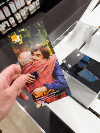 POV male hand reading instrcutions on the booklet for the MasterCard Orange Bank card advertising on the dedicated showcase in telecommunication branch Storeのeditorial素材