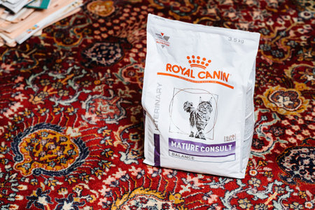 Open package with Royal Canin Mature Consult cat dry pet food on the silk rug in living room -...