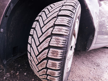 Car front with winter tire covered with dust - brand new wheels for the upcoming cold season