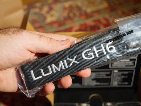 Male hand holding shoulder strap for the new Panasonic Lumix GH6