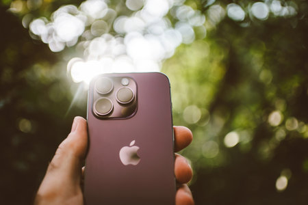 Male hand holding new Apple iPhone 14 Pro with triple-camera on the rear and silver shining logotypeのeditorial素材