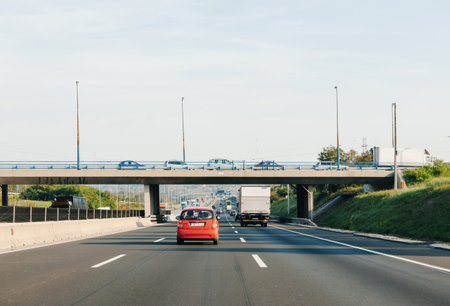 Rear view of red car and truck driving on Hungarys highway with bridge full of cars aboveのeditorial素材