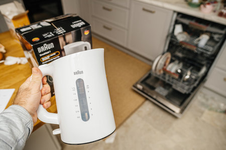 male hand holding Braun Coffee Maker and Kettle in the modern kiのeditorial素材