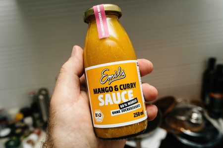 Male hand holding in kitchen bottle with Emails Mango and Curry sauce