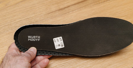 Male hand holding new Wurth Modyf protective shoe inner sole black background