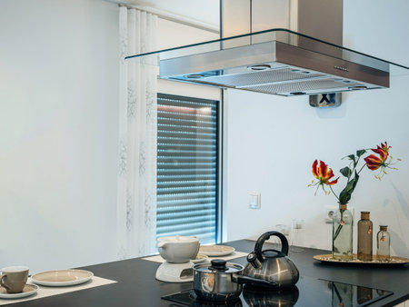 A modern kitchen showcases a stylish hanging extractor over an island, with neat decor enhancing the culinary spaces charmの写真素材