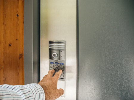 A man presses the access code on the intercom device to enter his house, which incorporates a surveillance CCTV camera for securityの写真素材