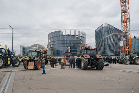 Strasbourg, France - Feb 6, 2024: Demonstrators employ tractors to obstruct EU Parliament entrance, decrying lower food standards and new GMOs.のeditorial素材