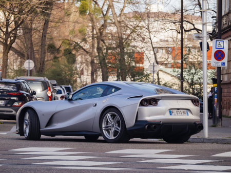 Strasbourg, France - Mar 20, 2024: A sleek silver sports Ferrari car driving on the side of a road, reflecting the sunlight, with no one around.のeditorial素材