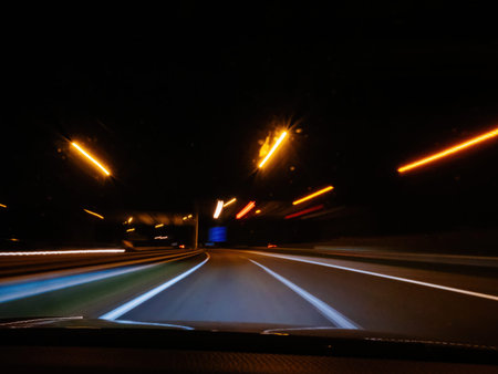 A nighttime highway scene with streaks of light from street lamps and passing vehicles creating...