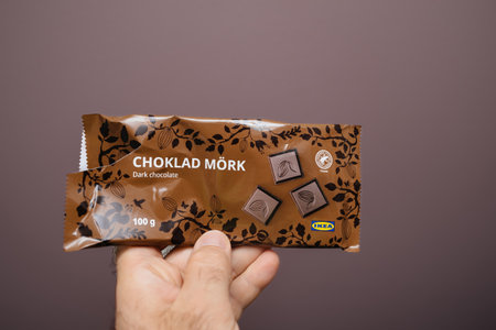 Bonn, Germany - May 5, 2024: Hand holding a Choklad Mork dark chocolate bar from IKEA, emphasizing the packaging design and branding against a plain background.のeditorial素材