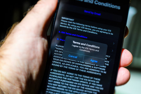 London, UK - Sep 28, 2023: A male hand holds the iPhone 15 Pro Max during setup and unboxing, agreeing to the terms and conditions notification. This marks the beginning of using the deviceのeditorial素材
