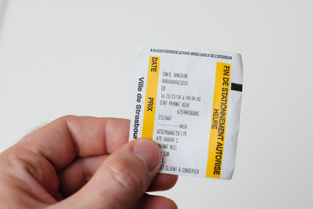 Strasbourg, France - Jan 14, 2015: Hand holding a parking ticket issued in Strasbourg, France, showing detailed information including date, time, location, and payment methodのeditorial素材