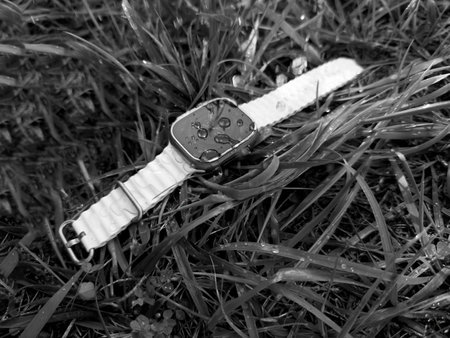 Paris, France - Sep 23, 2022: Apple Watch Ultra 2 adventure smartwatch from Apple computers lying in monochrome grass with waterdrops on the display, highlighting its waterproof capabilities and rugged designのeditorial素材