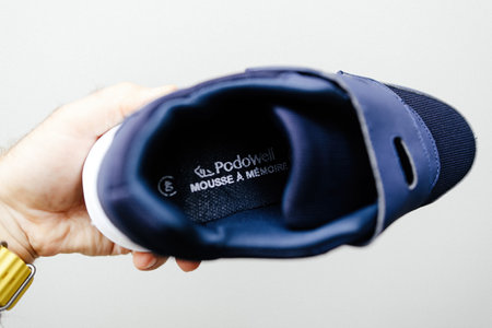 Paris, France - Jun 22, 2024: A male hand holding a pair of Podowell brand comfortable shoes designed for seniors with foot health issues, featuring cushioned soles, supportive insoles, and a sleek, easy-to-wear design, with a mouse and a memory foam inseのeditorial素材